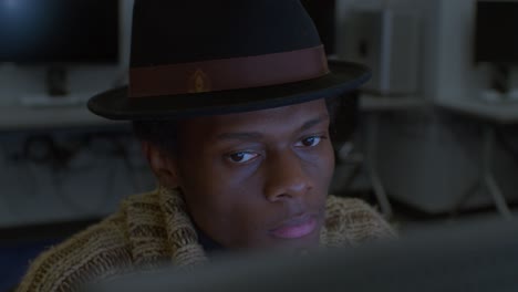 Developer-with-black-fedora-hat-Working-On-Computer-In-Lab---high-angle