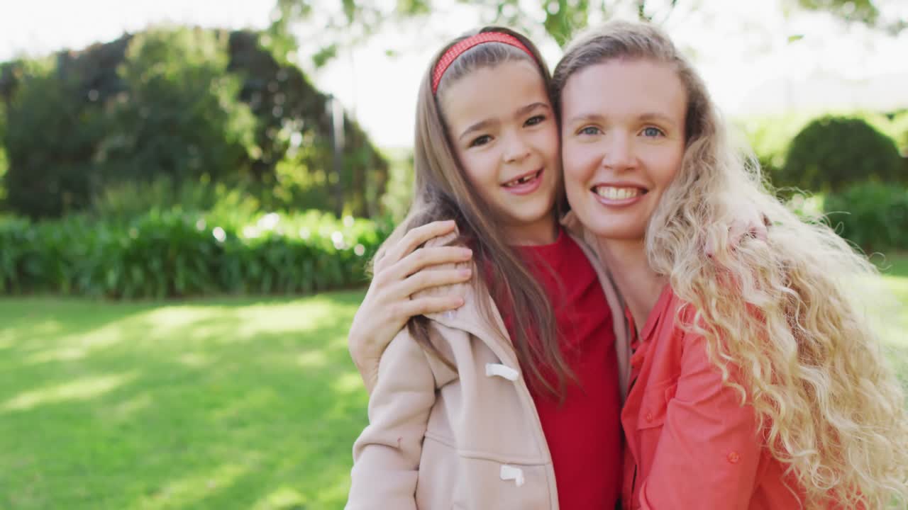 retrato de video de una madre caucásica feliz abrazando a su hija sonriente en el jardín