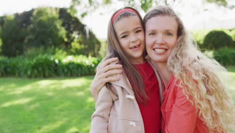 video portrait of happy caucasian mother embracing with smiling daughter in garden