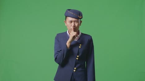 asian woman air hostess looking at camera and making shh gesture in the green screen background studio