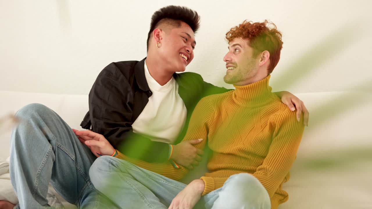 Happy Gay Couple Cuddling and Laughing on Sofa at Home