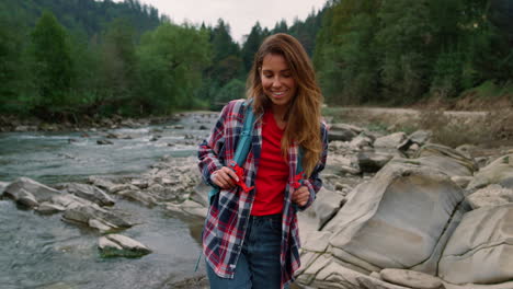 traveler hiking along river in mountains. smiling woman walking at river