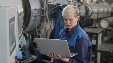 female factory worker using laptop to operate machinery