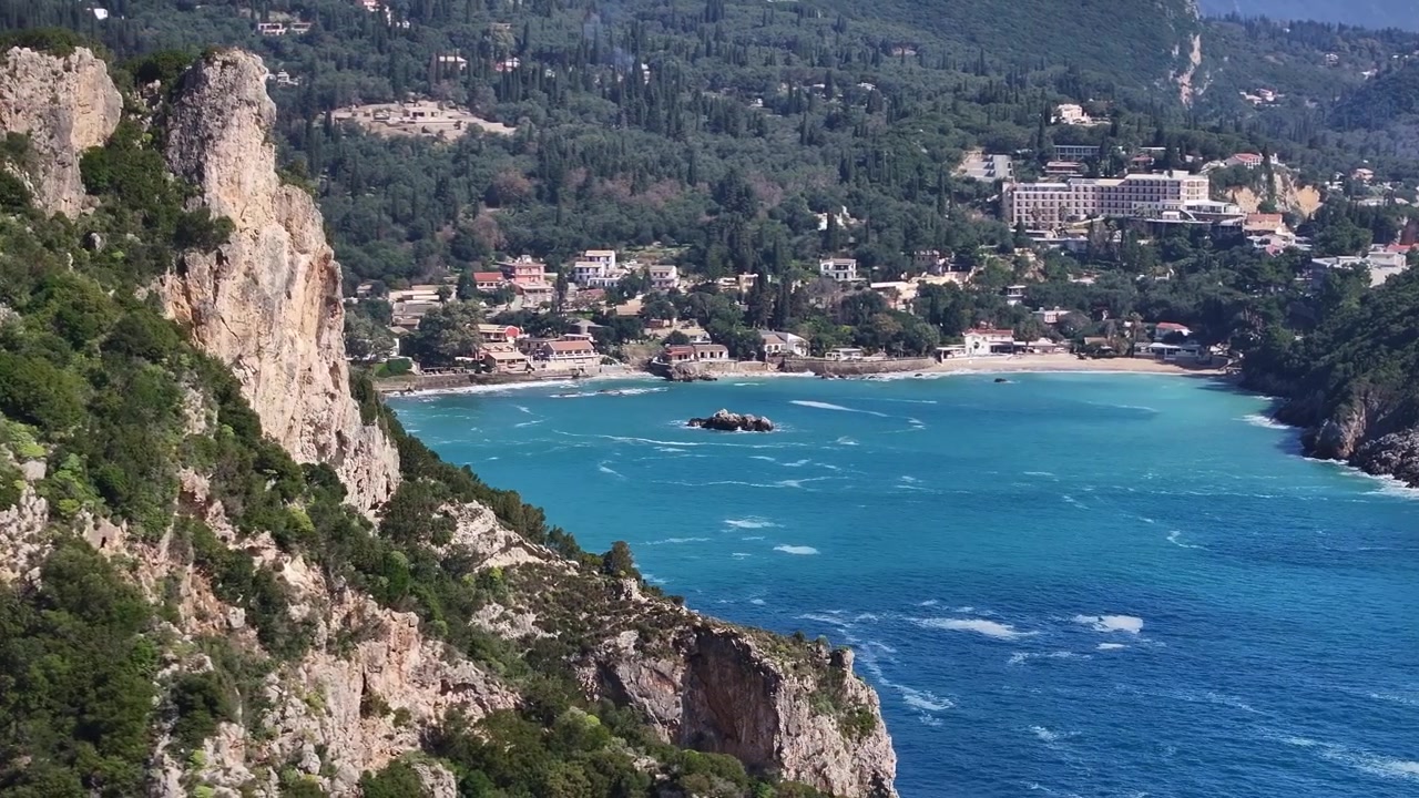 Vista aerea panoramica dalle lussureggianti scogliere verdi che rivela le acque cristalline turchesi della spiaggia di Agios Spyridon a Paleokastritsa, Corfù. Ispira pura beatitudine costiera