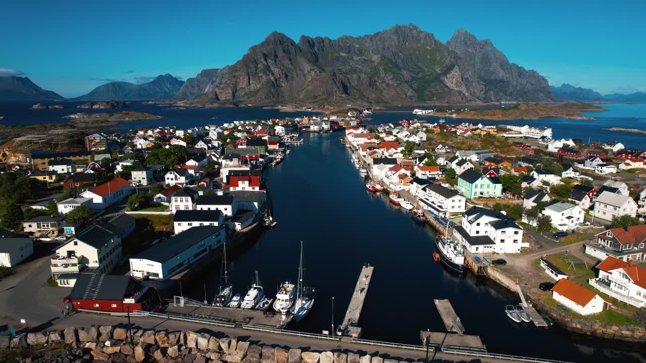 Henningsvær aerial showing the town, harbor, and mountain peaks of the Lofoten islands in Norway.