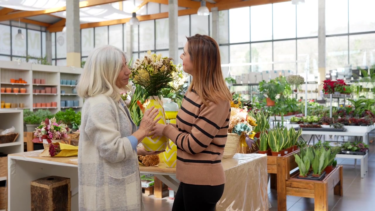 Duas Mulheres Discutindo um Arranjo de Flores em um Centro de Jardinagem.