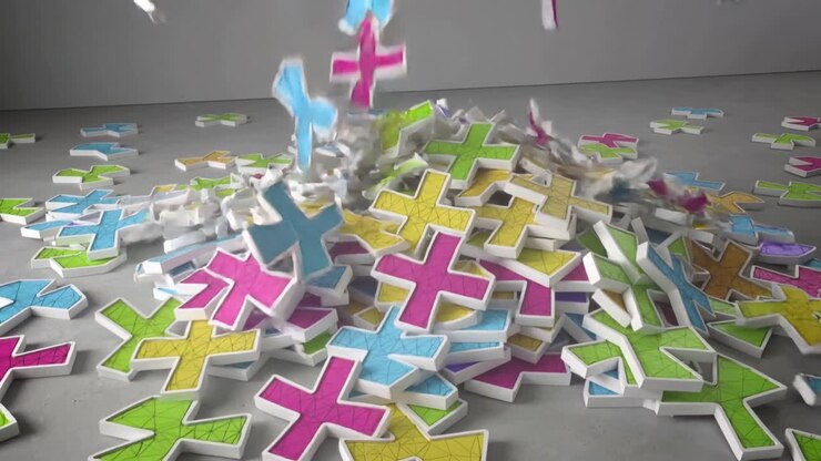 Falling off-frame white-edged plus-shaped pieces striking central pile on grey floor, forming heap