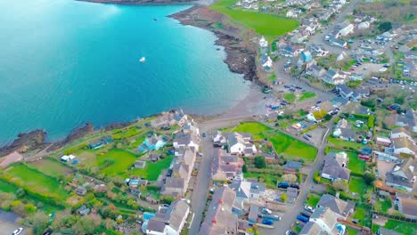 Flying-overhead-Moelfre-village-Anglesey,-towards-the-beach-with-view-of-the-sea-and-seaside-buildings