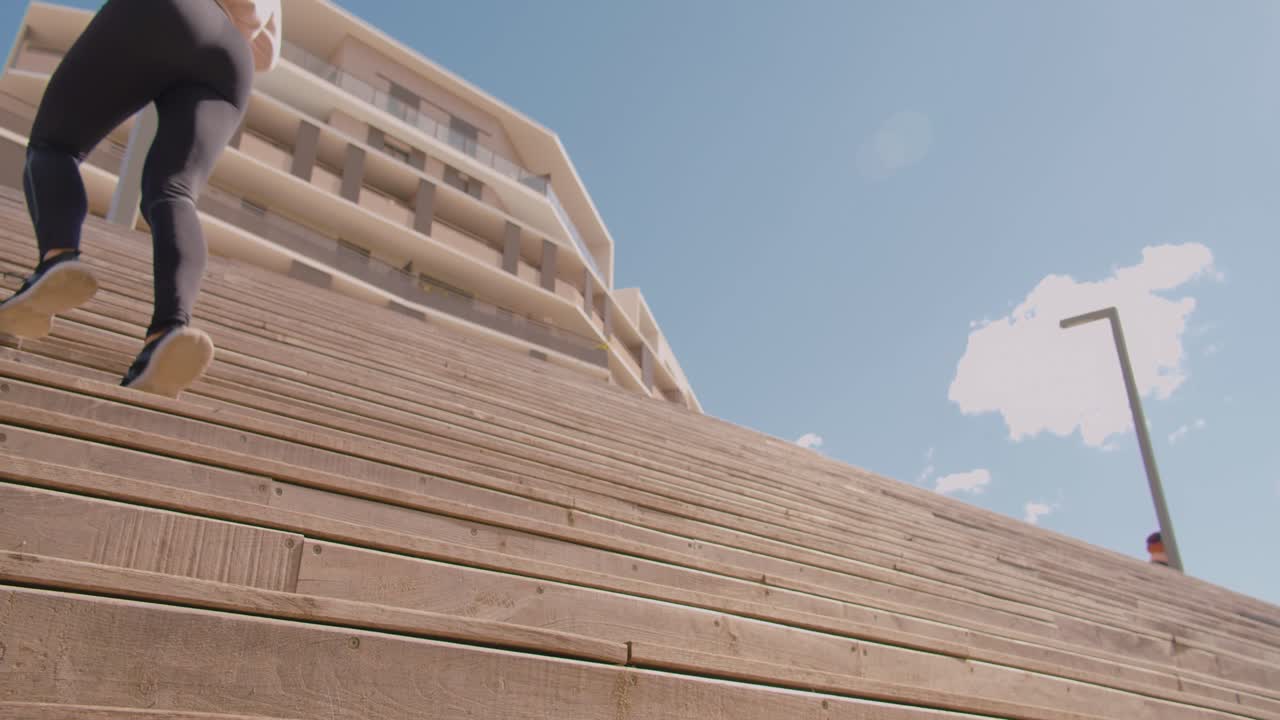 타이트한 검은색 요가 바지를 입고 계단을 뛰어오르는 매력적인 여성, 정적인 전망