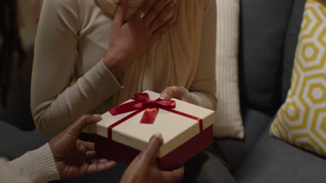 close up of woman giving female friend birthday present at home with party balloons in background 3