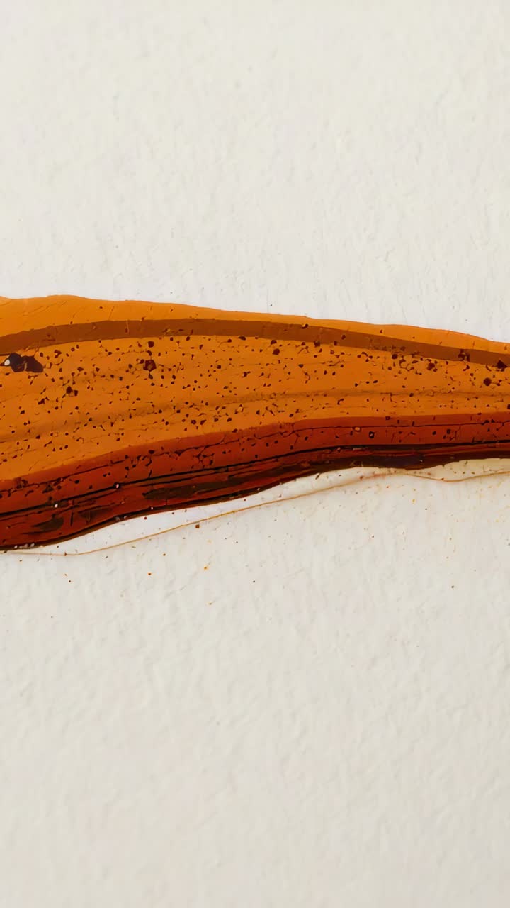 Vertical video: Settling orange-brown pigment band on white panel from tiny motion across frames