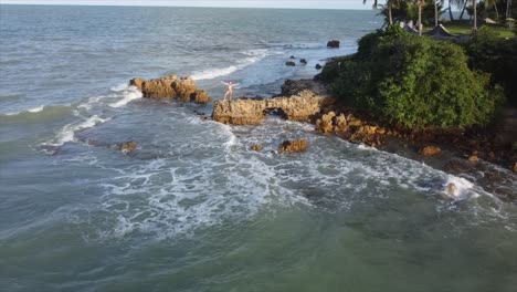 girl standing on rock on the edge of brazils ocean sunshine and love