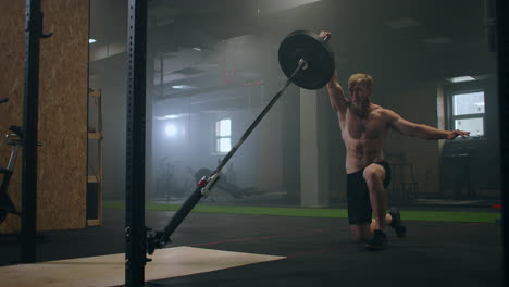 A-male-athlete-lifts-a-weight-bar-with-one-hand-in-slow-motion.-Strength-training-for-a-boxer.-The-man-is-sweating-working-out-in-the-gym-practicing-the-force-of-the-blow-with-his-hand