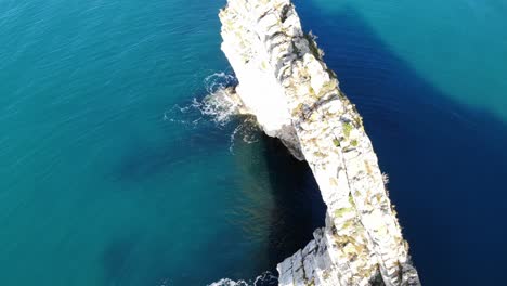 Aerial-Over-Durdle-Dor-Arch-Looking-Down-Surrounded-By-Calm-Turquoise-Waters