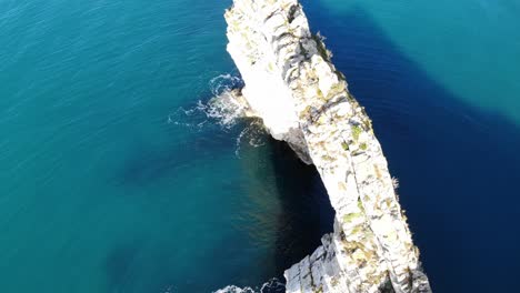 antena sobre el arco de durdle dor mirando hacia abajo rodeado de tranquilas aguas turquesas