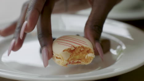 an attractive woman picks up a delicious macaroon cookie and takes a bite