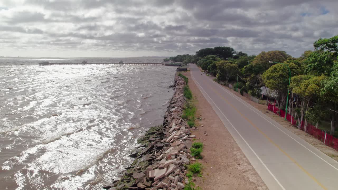 Aerial view of the shoreline in Punta Lara, Buenos Aires, showcasing the riverfront road and rocky edges.