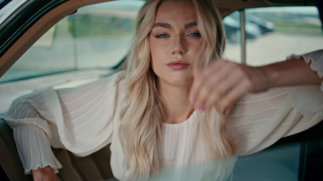 mujer hermosa posando en el asiento trasero del automóvil mirando a la cámara con confianza de cerca.