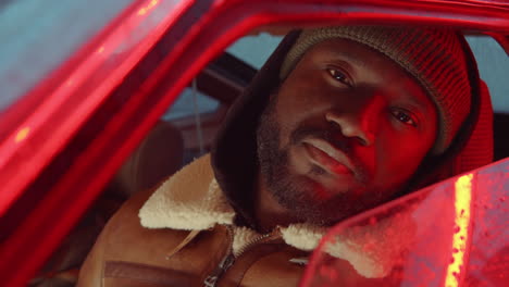 hombre afroamericano en el coche y posando para la cámara