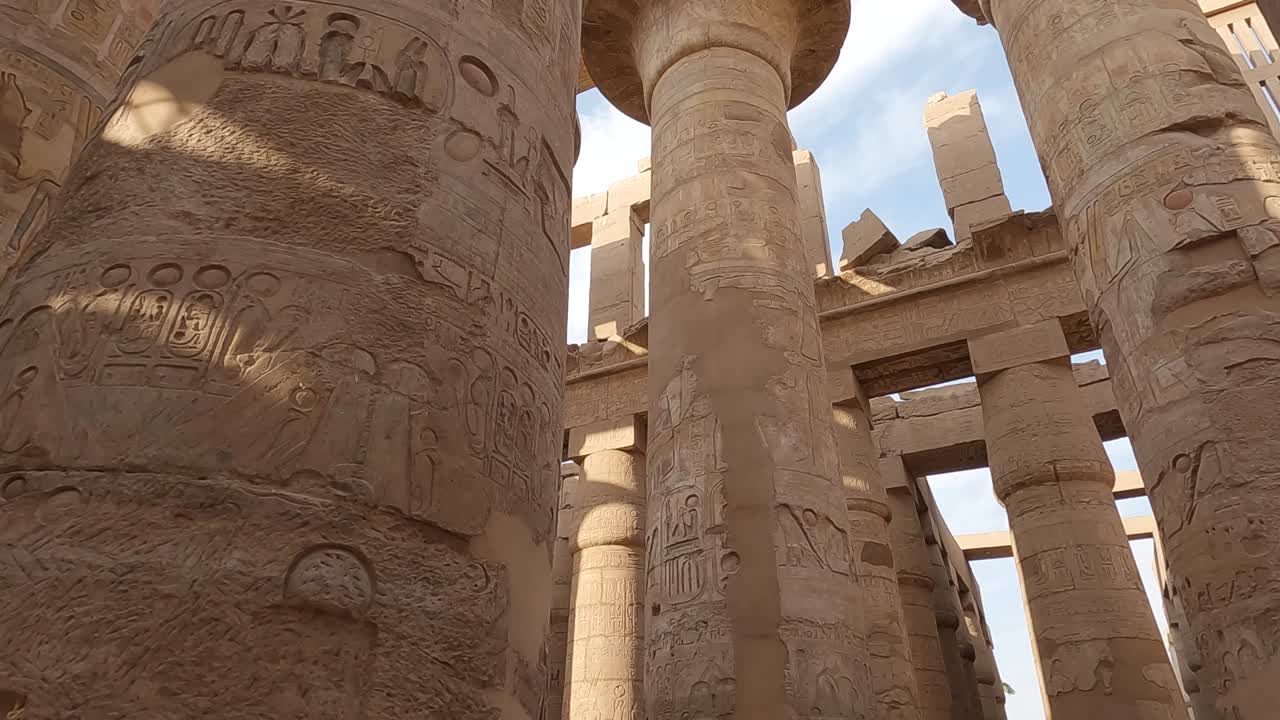 pov mirando hacia arriba y caminando suavemente pasando columnas de arenisca en el complejo del templo de karnak en egipto