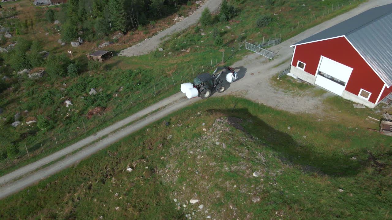 보관을 위해 베일드 사일리지를 헛간으로 옮기는 트랙터