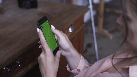 mujer usando un teléfono inteligente con pantalla verde en un estudio