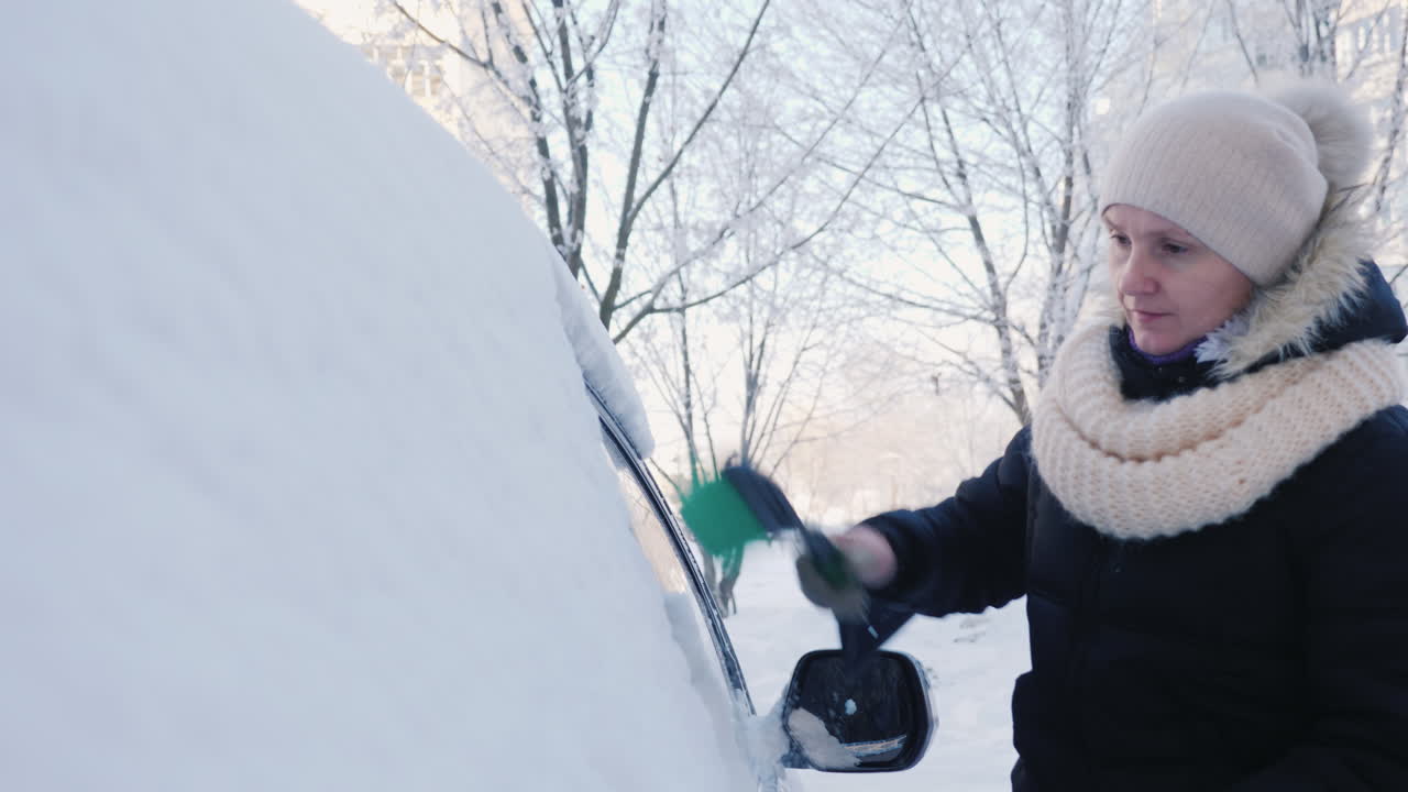 una mujer quita la nieve de su coche