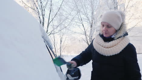 a woman removes snow from her car