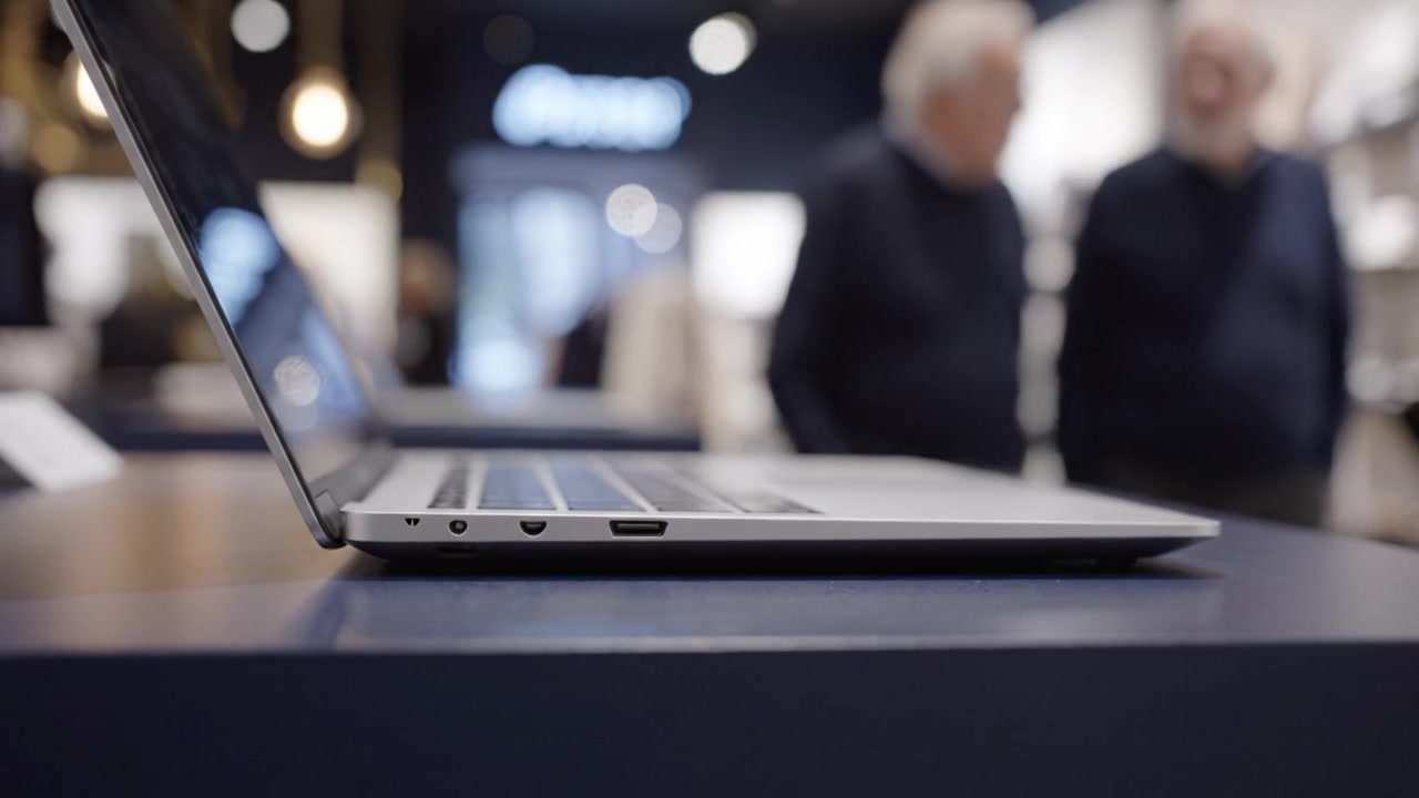 Laptop elegante che mostra design e funzionalità moderni, catturando potenziali acquirenti in un ambiente di vendita al dettaglio raffinato con illuminazione soffusa e uno sfondo accattivante