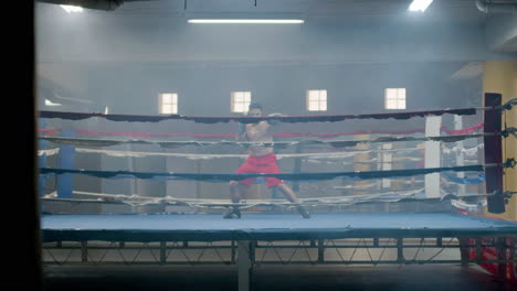 strong male athlete doing shadow fight in boxing gym