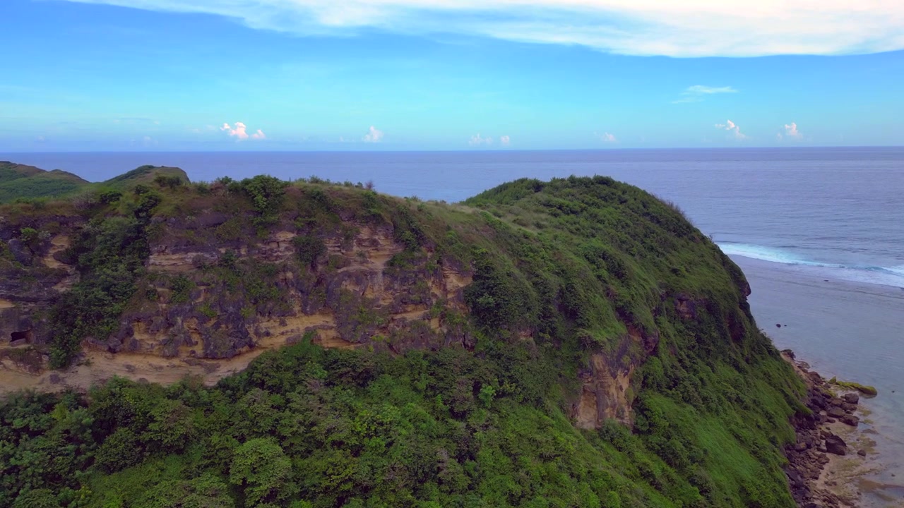 Quang cảnh bờ biển đảo Lombok cho thấy những ngọn đồi xanh gặp gỡ đại dương xanh trong vắt với rạn san hô nông và những con sóng nhẹ nhàng. Quang cảnh tuyệt đẹp từ trên cao, toàn cảnh được quay bằng drone