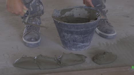 labor man spreading concrete cement on the floor from bucket with small shovel