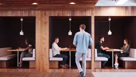 hombres y mujeres de negocios vestidos casualmente se reúnen y trabajan en cubículos en oficinas modernas filmadas en cámara lenta