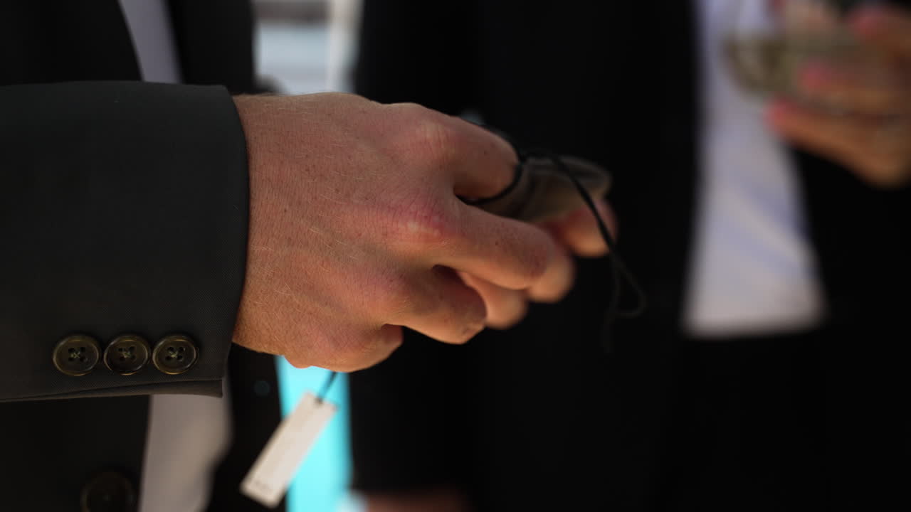 un novio en un esmoquin jugando con un anillo de boda de plata en la mano