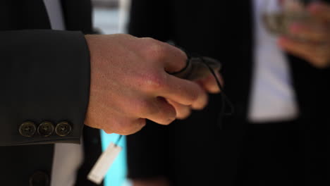 a groom in a tux playing with a silver wedding ring in his hand