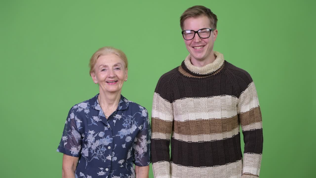 Happy grandmother and grandson smiling together against green background