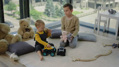 Older-brother-offering-younger-brother-game-home.-Cute-siblings-playing-together