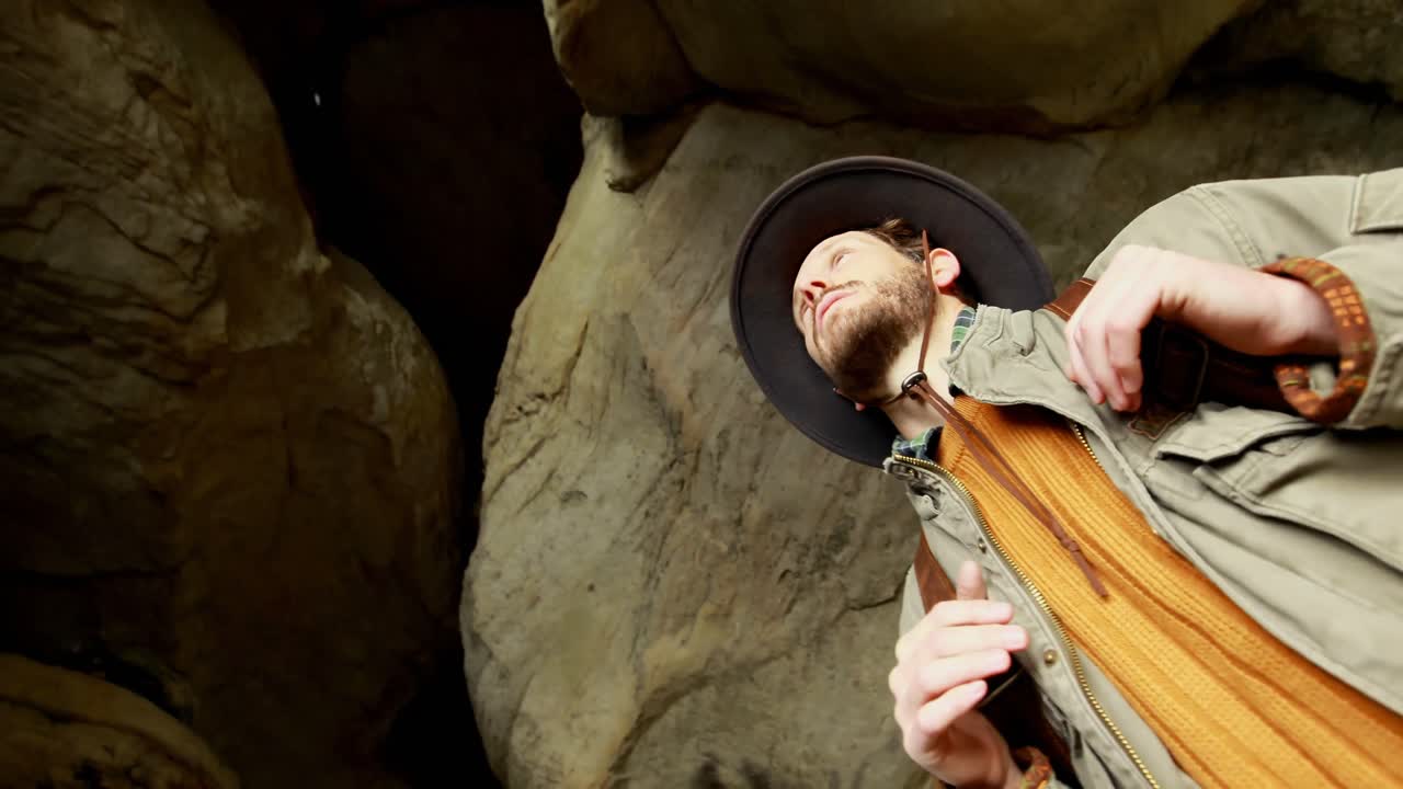 Male hiker standing with backpack in the cave 4k