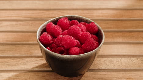 hand picking raspberries from bowl