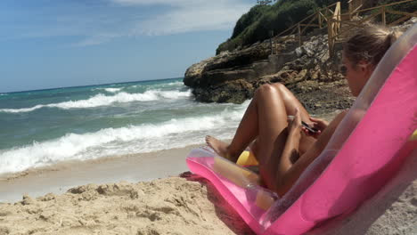 Schönes-Mädchen-Mit-Blonden-Haaren-Entspannt-Sich-Auf-Einer-Rosa-Luftmatratze-Am-Strand-Von-Mallorca