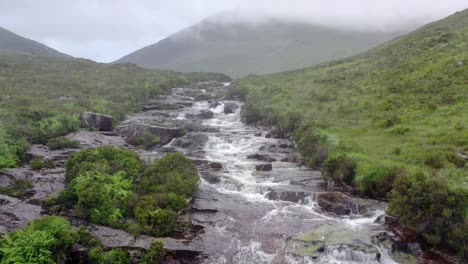 agua corriendo en el acantilado de esquisto corriendo por una cascada gloriosa en un día nublado con niebla que cubre la cima de la montaña en el fondo