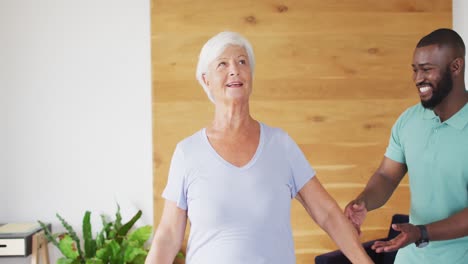 video of happy african american male physiotherapist examining caucasian senior woman