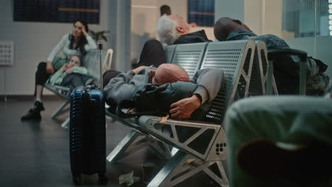 tired passengers sleeping in airport waiting area