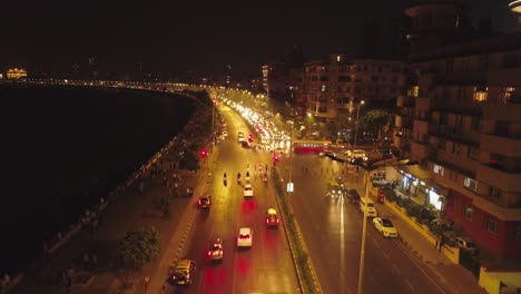 an aerial view with cinematic drone movement of the iconic marine drive nightlife with air india and trident hotel buildings in sight.