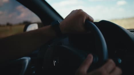 Mano-En-El-Volante-Conduciendo-Por-Una-Carretera-Rural