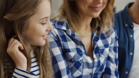 close up of the nice happy family of parents and two kids sitting close to each other and looking at something with smiles