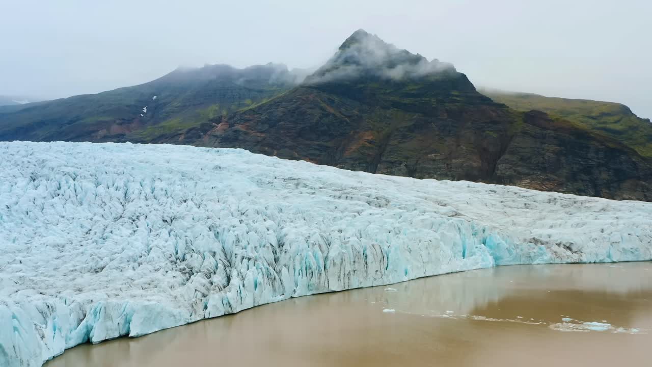 un metraje cinematográfico de 4k, filmado en cámara lenta, muestra vistas dramáticas y distintivas de glaciares engrosados con un pico de montaña en el fondo