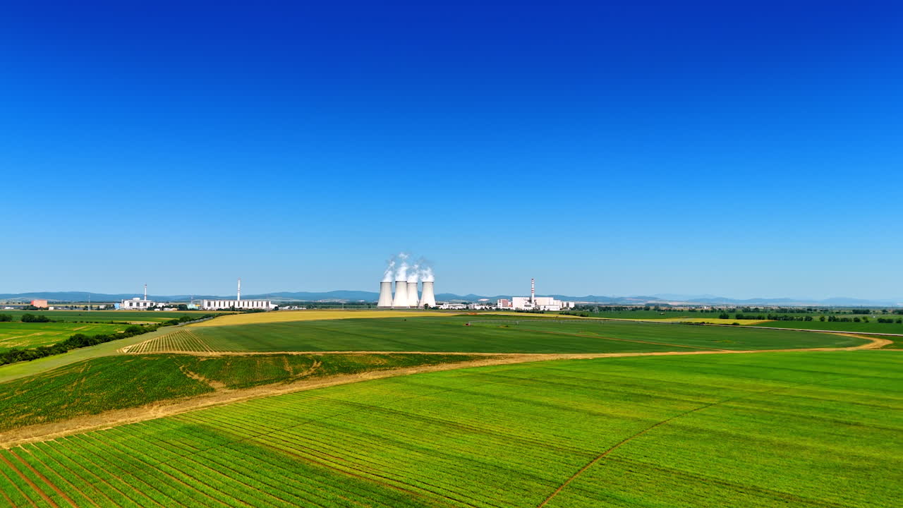 Vast agricultural fields in the rural area. Approaching the industrial plant working in the countryside
