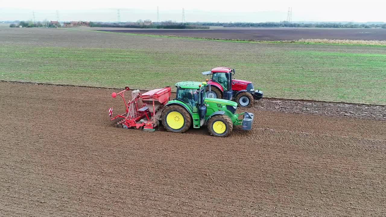 Two tractors working in a field sowing the next crop of wheat.
