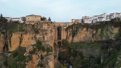 Ronda-Bogenbrücke,-Wasserfall-Und-Stadtbild-In-Malaga,-Andalusien,-Spanien---Luftaufnahme-Rückwärts